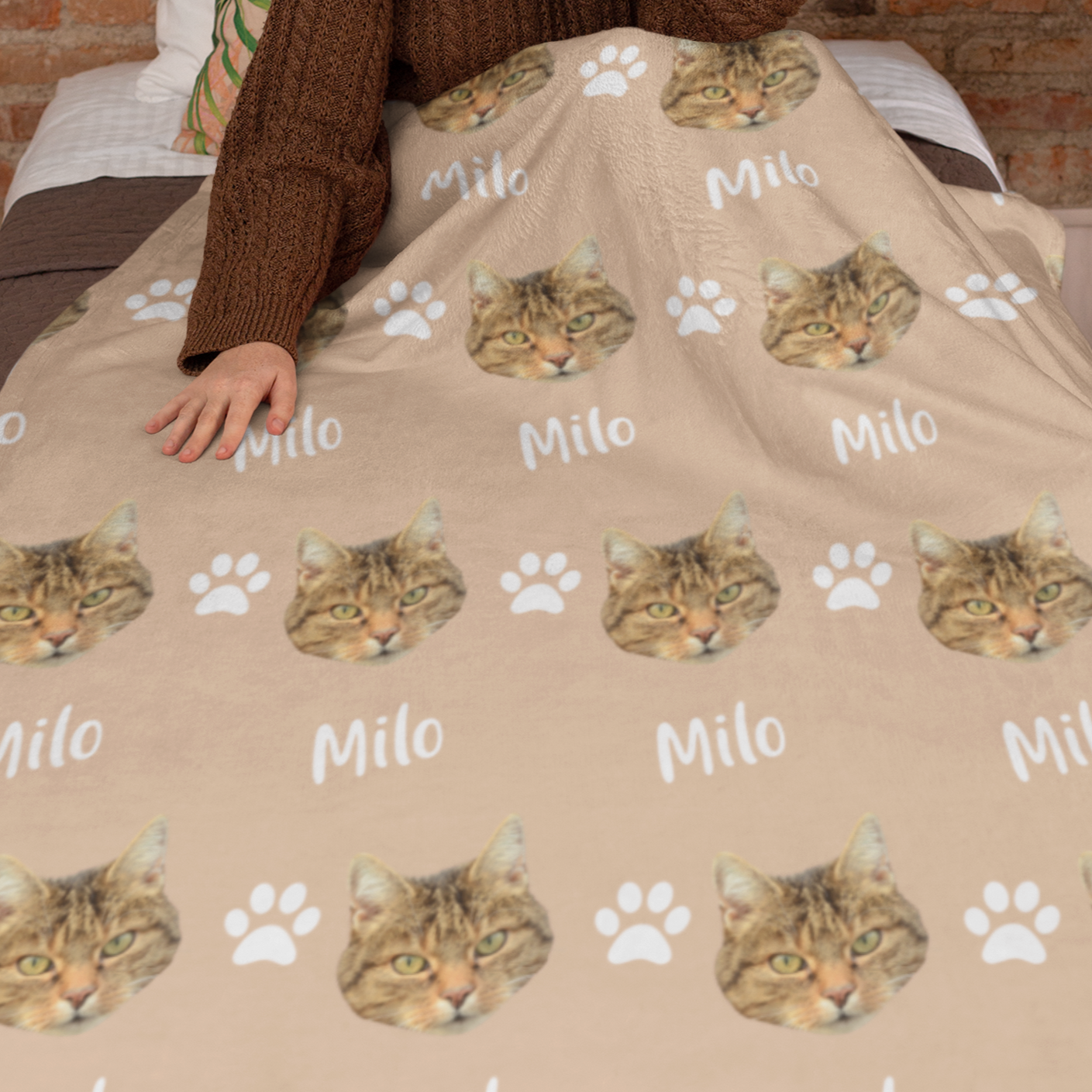Woman holding a blanket showcasing a custom chosen cat head design with a personalized name below.