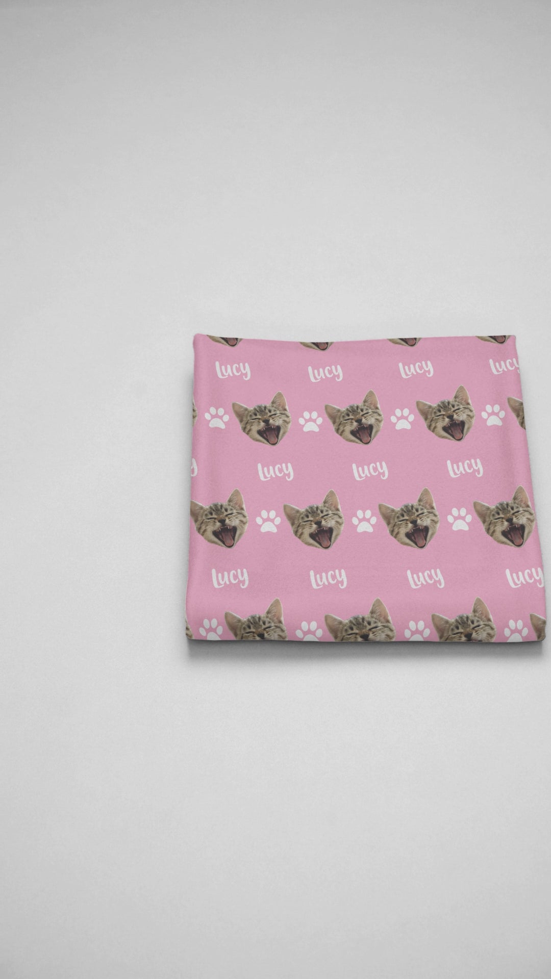 Video showcasing a folded blanket with a customized cat head design and personalized name displayed.
