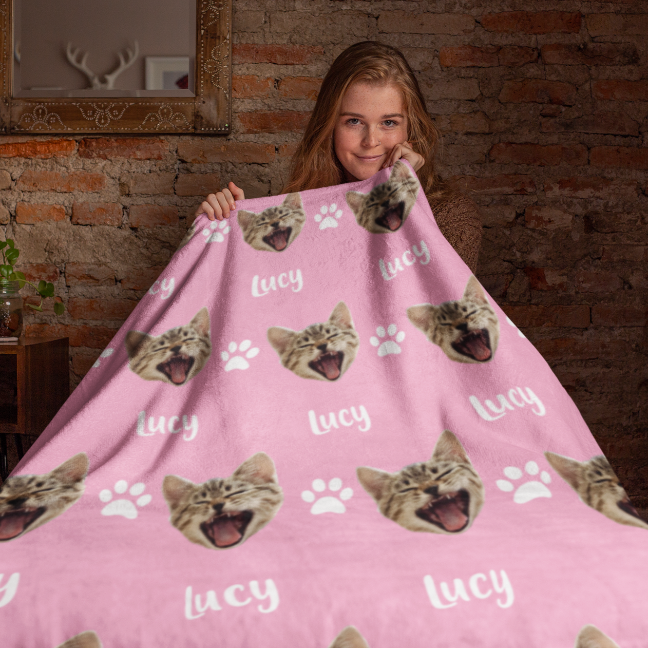 Woman holding a blanket showcasing a custom chosen cat head design with a personalized name below.